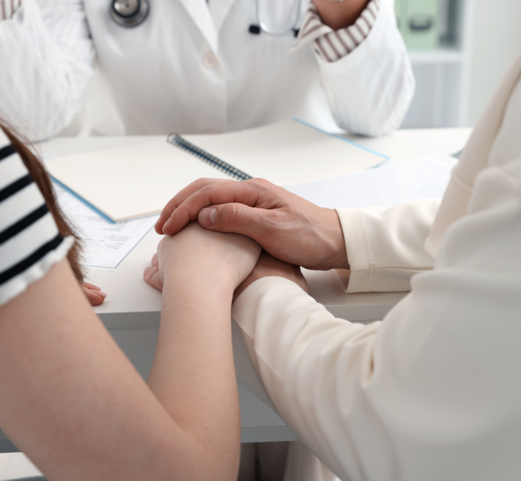 couple qui se tient la main devant un médecin